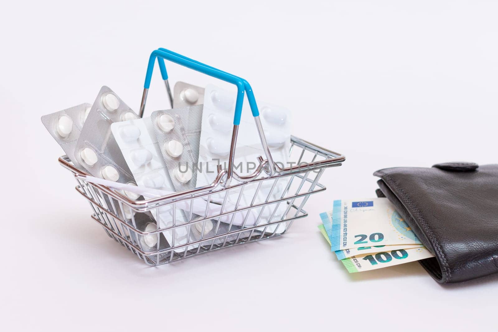 Expensive Medicine and Inflation Concept: Pills and Capsules in a Shopping Basket and Black Wallet with Euro Money on White Table. Global Pharmaceutical Industry and Big Pharma. Trade in Medicines