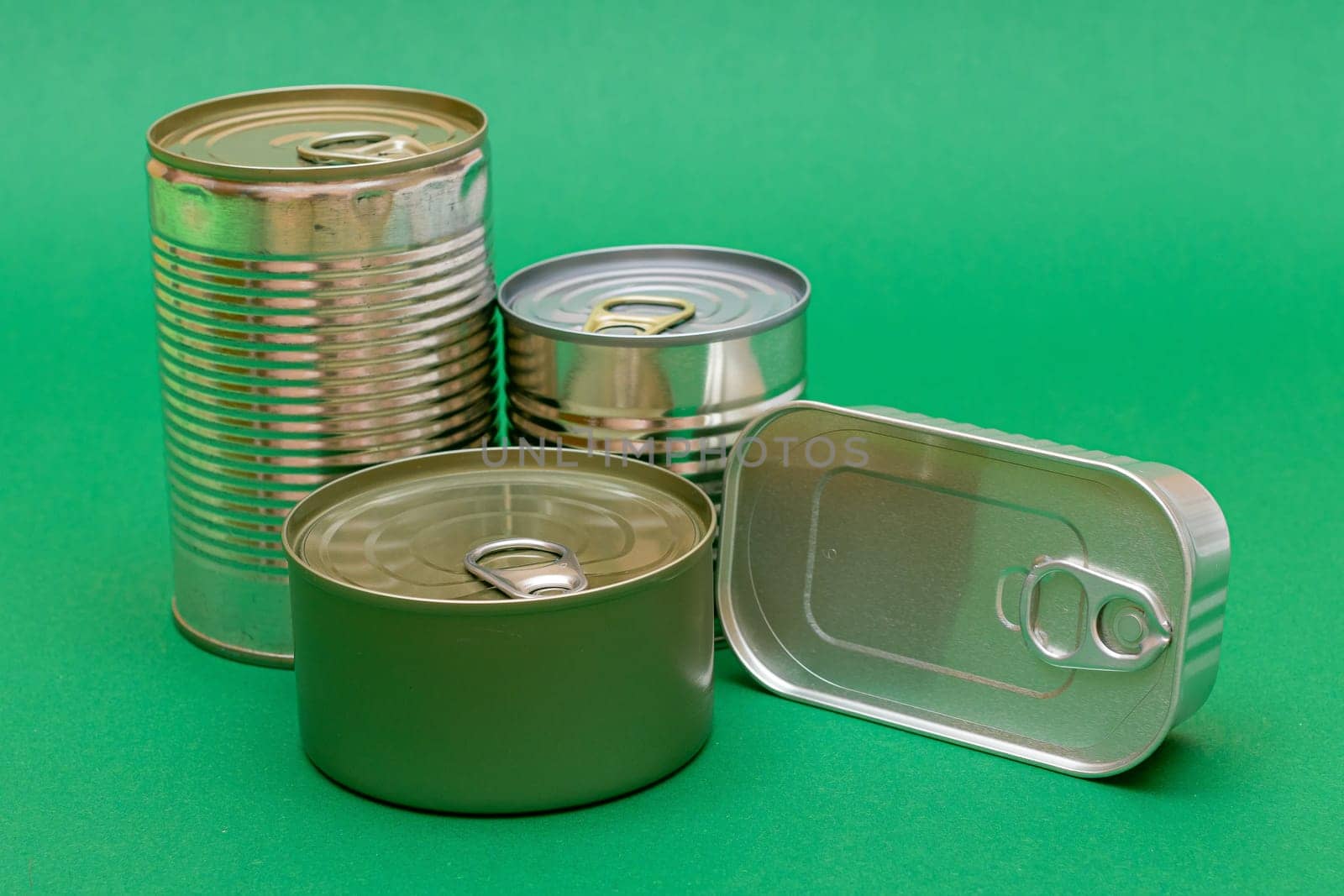 A Group of Stacked Tin Cans with Blank Edges on Green Background. Canned Food. Different Aluminum Cans for Safe and Long Term Storage of Food. Steel Sealed Food Storage Containers