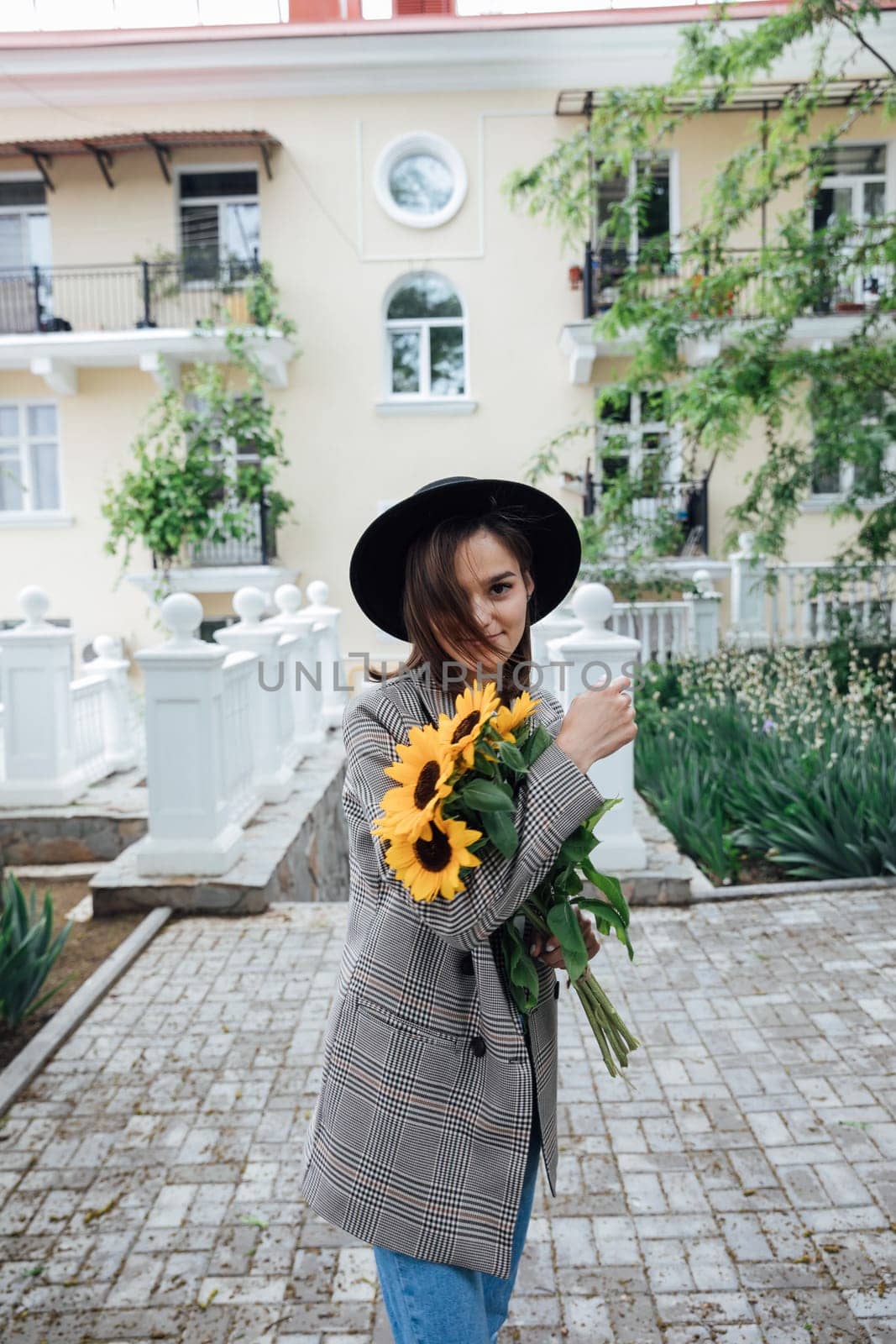 Woman in a hat with flowers posing for a walk near the house by Simakov