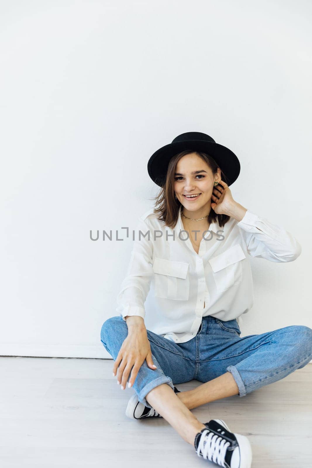 Woman in hat posing in bright studio by Simakov