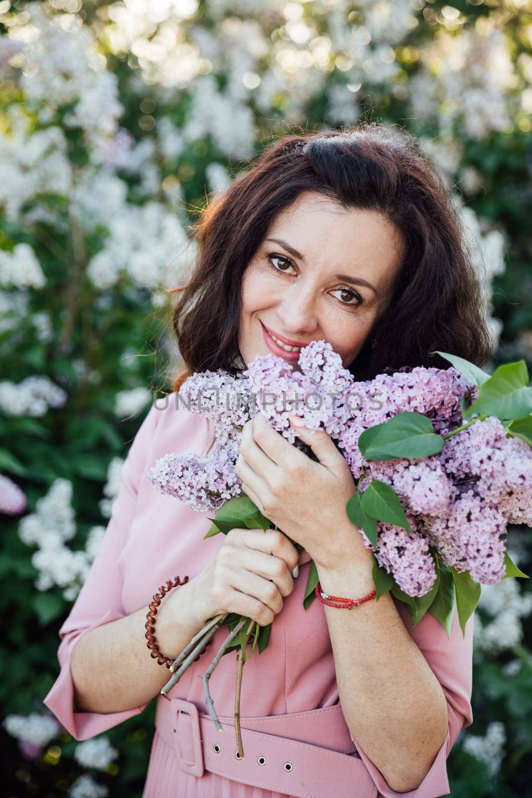 Beautiful woman with a bouquet of lilacs on a walk nature flowers