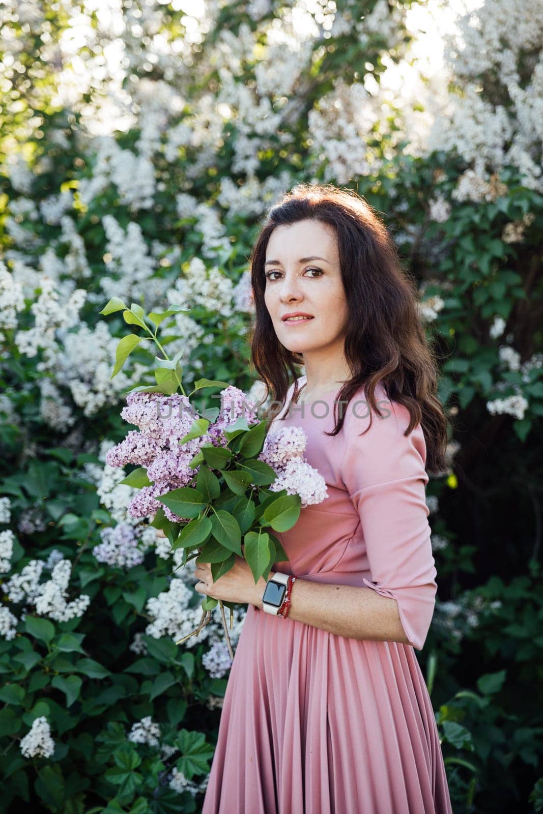 woman with a bouquet of lilacs on a walk nature flowers by Simakov