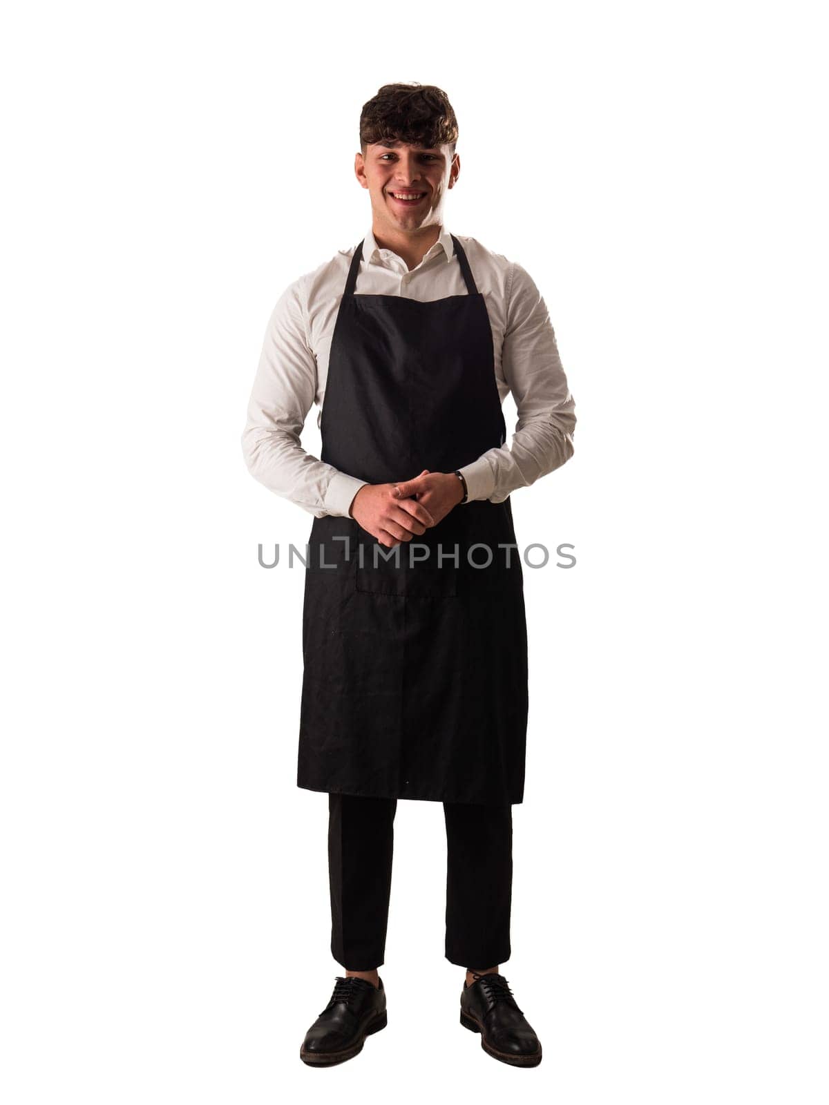 Full length shot of young chef or waiter posing, wearing black apron and white shirt isolated on white background