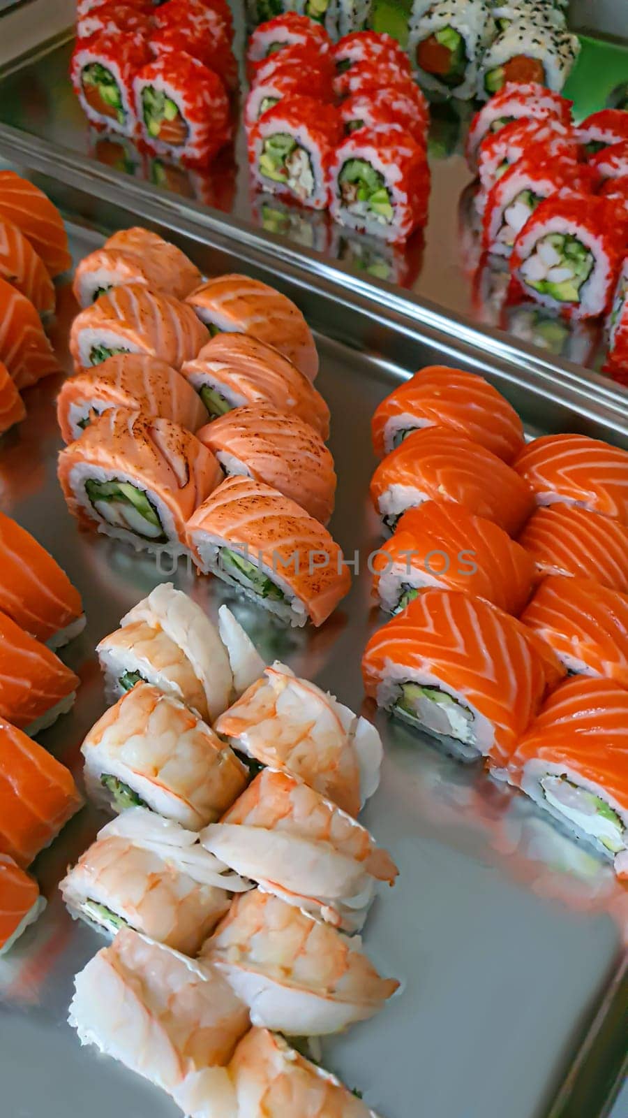 Sushi and rolls with caviar, shrimp and tuna, avocado on a gray background. Copy space