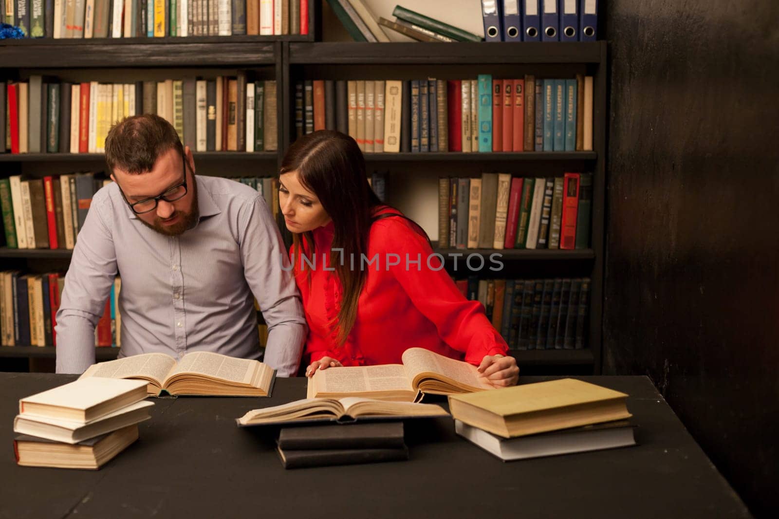 a man and a woman read a lot of books in the library by Simakov