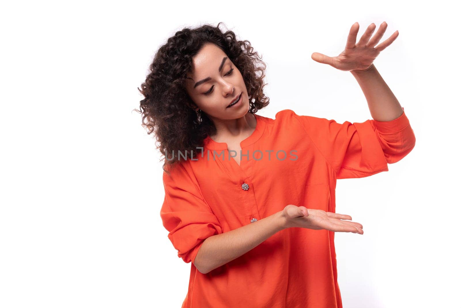 young pretty brunette woman dressed in an orange shirt points with her hands. advertising concept by TRMK