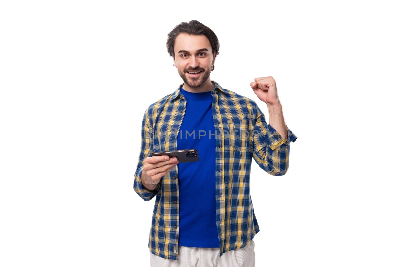 a young caucasian brutal man with an unshaven face dressed in a blue plaid shirt is watching a video on the phone.