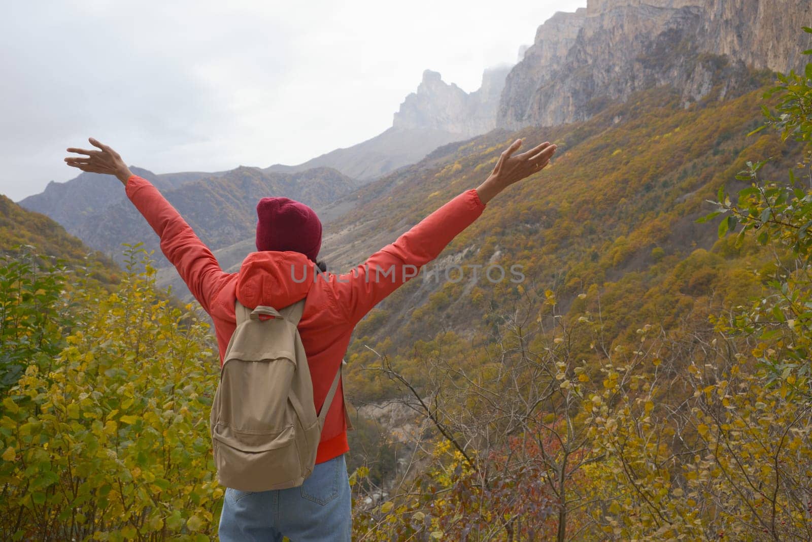 Woman outdoors exploring the Caucasus Mountains in Russia, travel, lifestyle, hiking, girl traveler raised her hands, active autumn holidays, hiking.