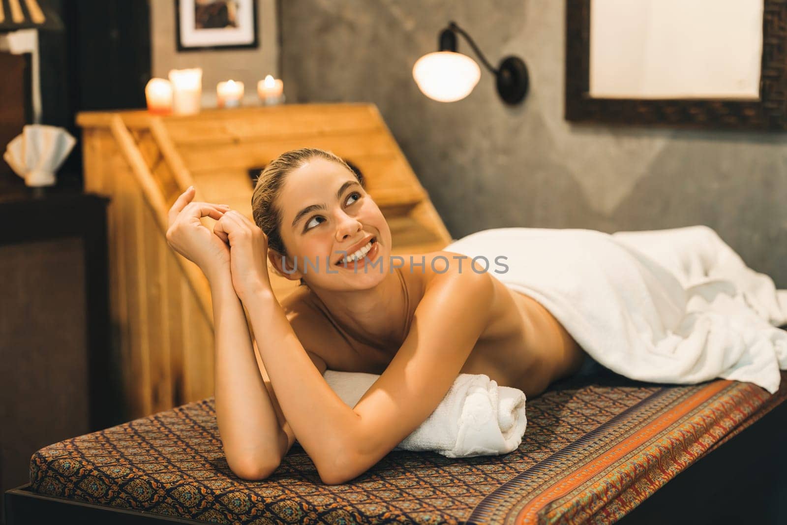 Portrait of beautiful caucasian woman in white towel woman lies on spa bed in front of warm wooden sauna cabinet with relaxation and peaceful at spa salon. Close up. A Side view. Tranquility.