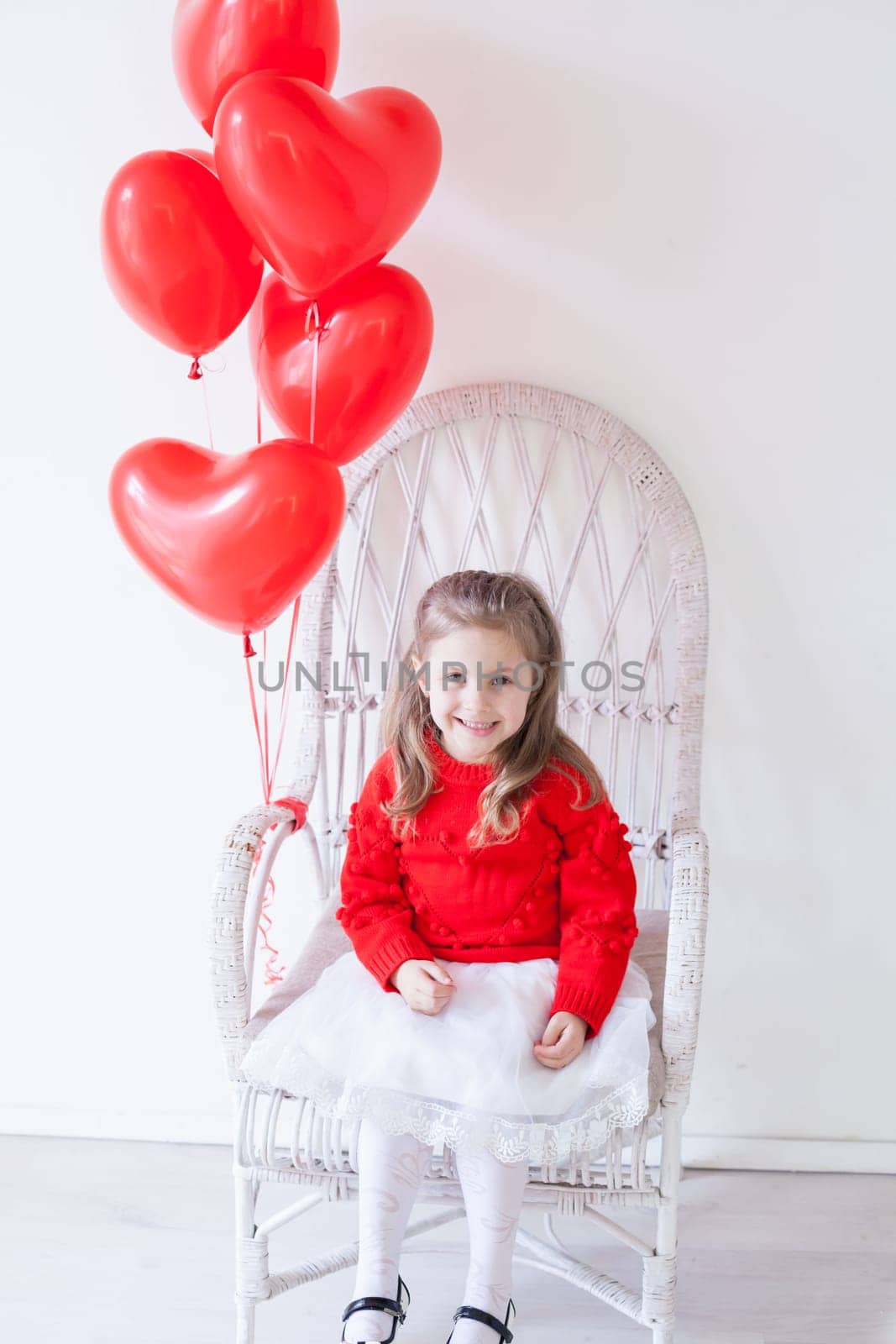 Beautiful little girl with red balloons in the shape of a heart by Simakov