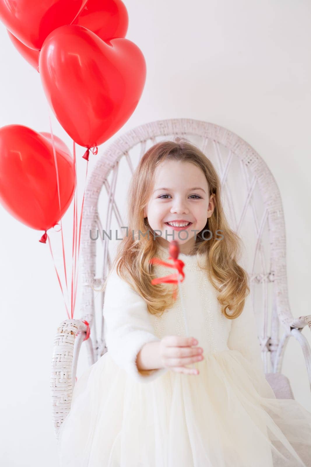 Beautiful little girl with red balloons in the shape of a heart by Simakov