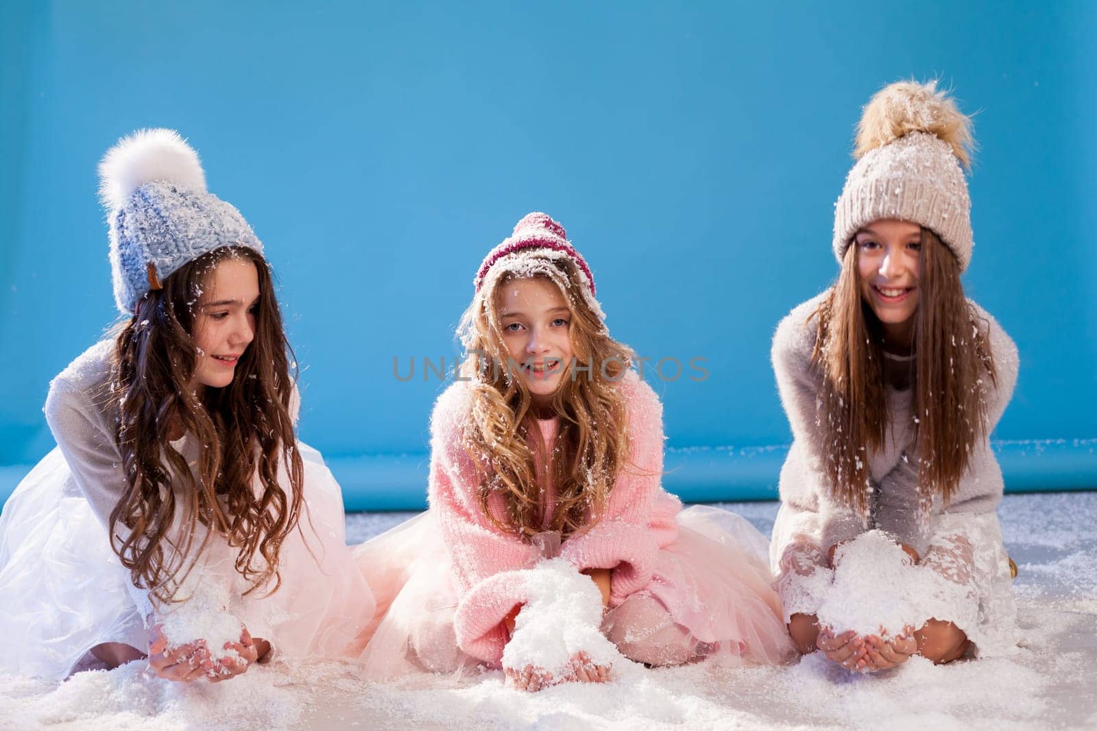 Three beautiful fashionable girls in winter cap snow chill January