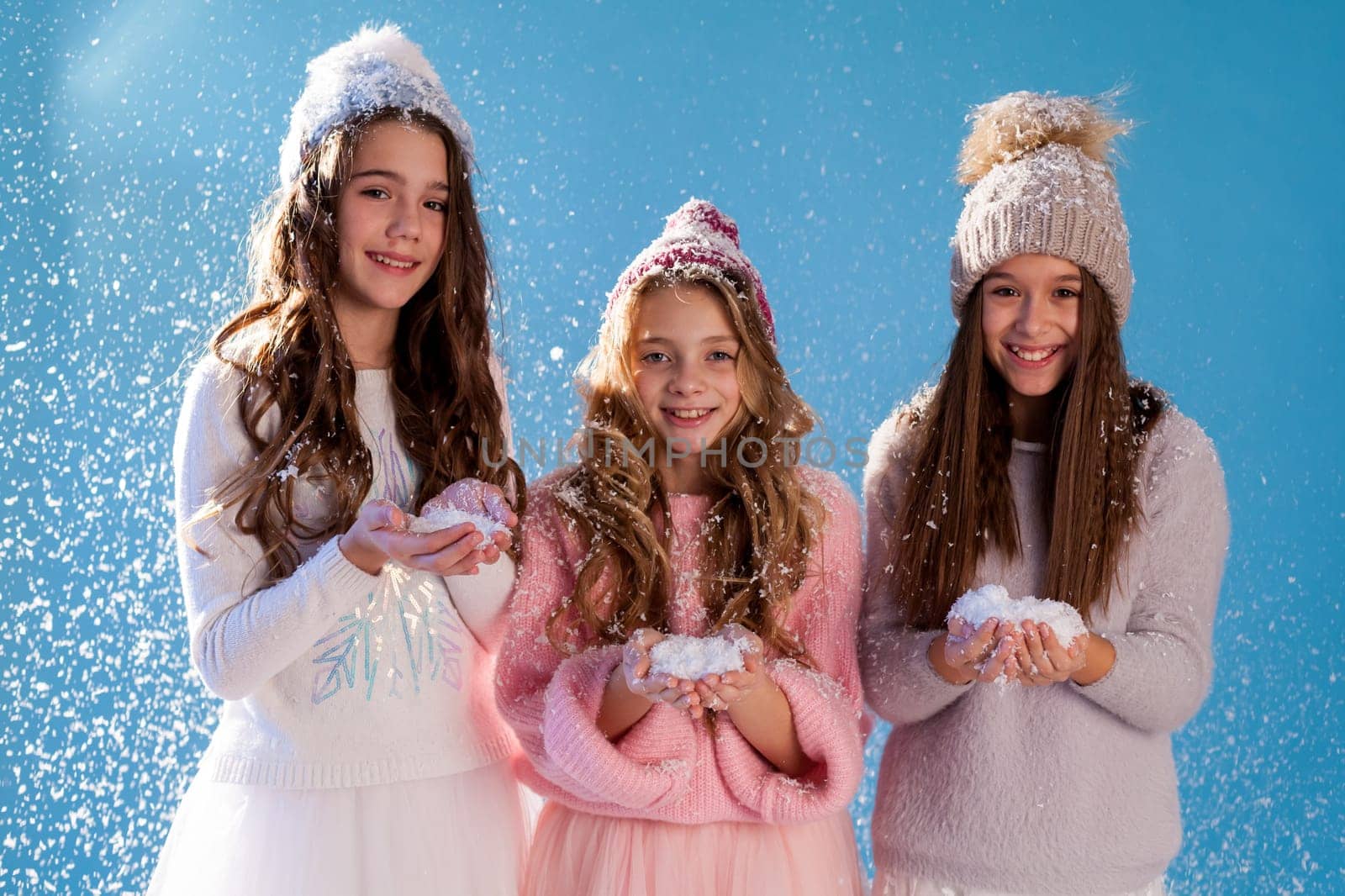 Three beautiful fashionable girls in winter cap snow by Simakov