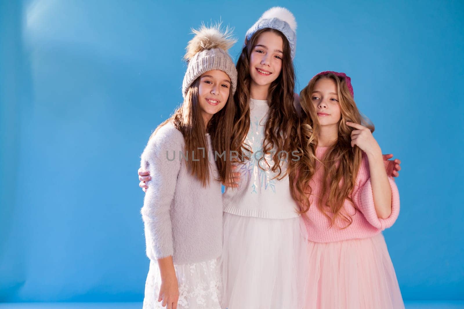 Three beautiful fashionable girls in winter cap snow by Simakov