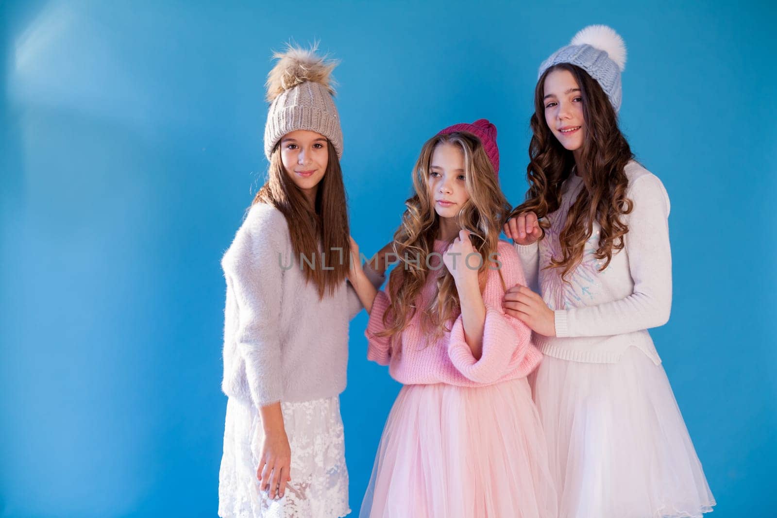 Three beautiful fashionable girls in winter cap snow by Simakov