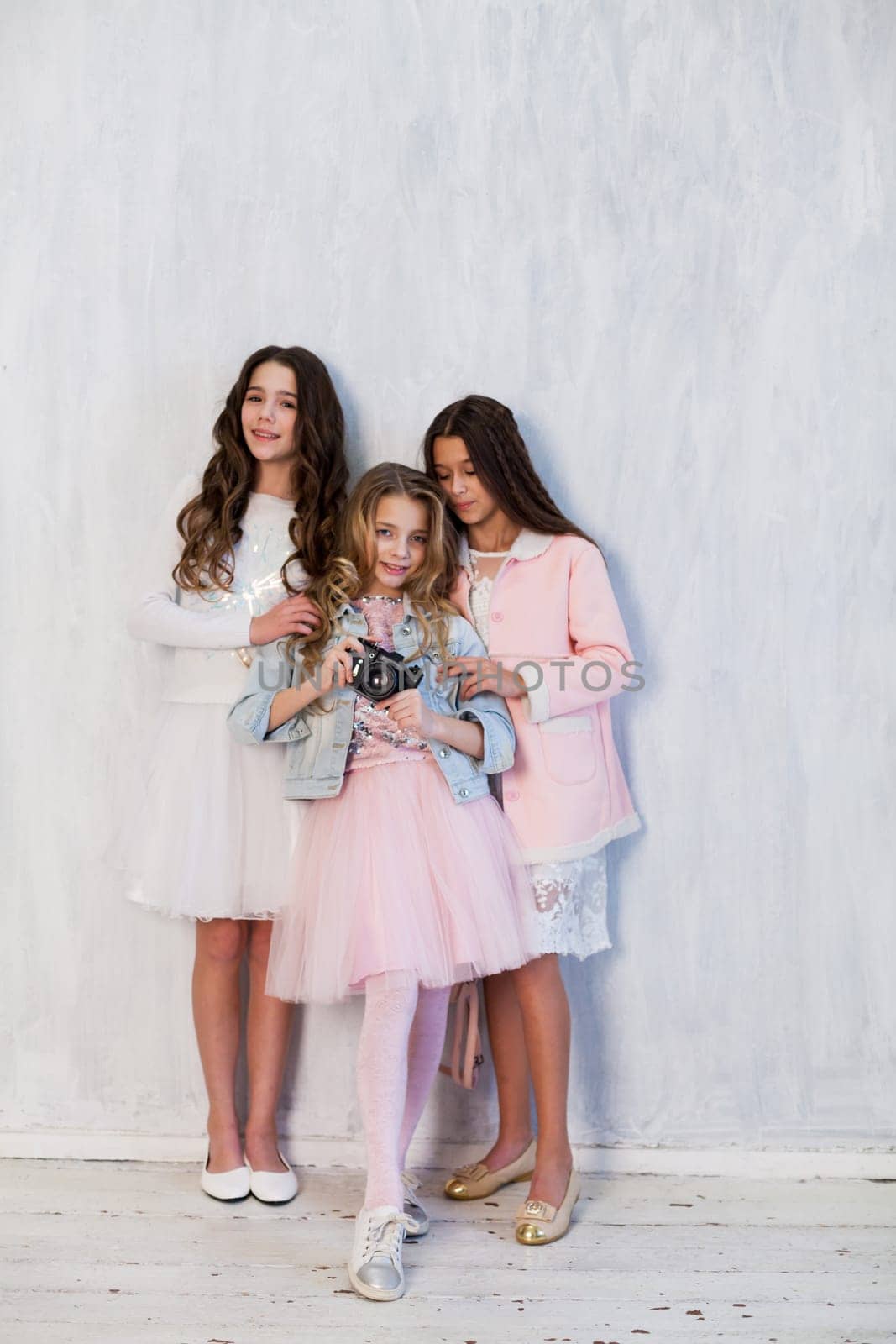 Three beautiful fashionable girls in white pink clothes at the photo shoot are photographed