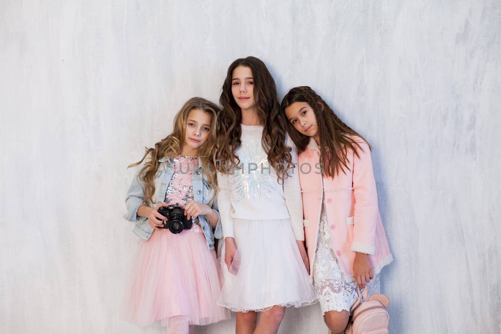 Three beautiful fashionable girls in white pink clothes at the photo shoot are photographed