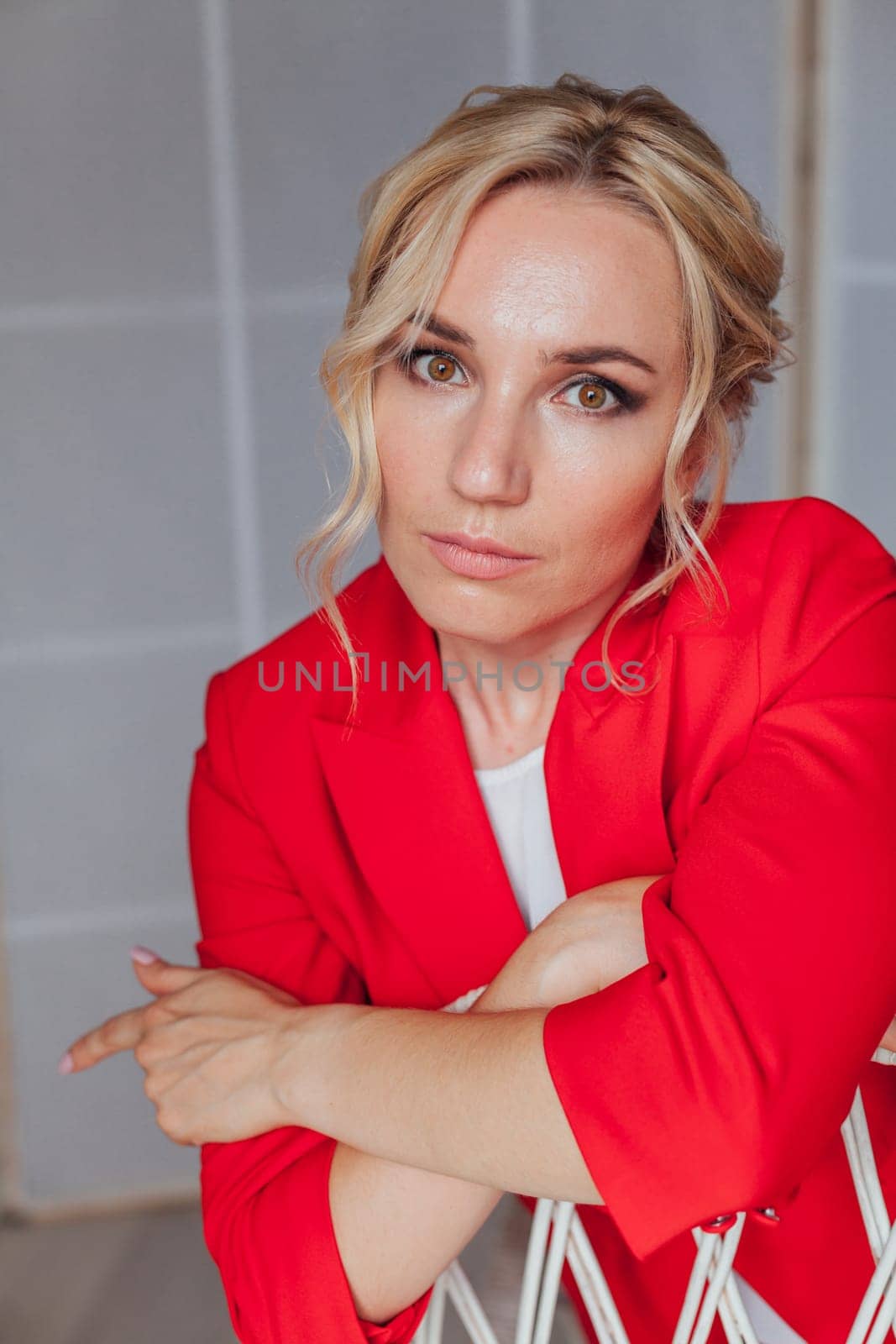 Portrait of a beautiful business woman in a red business suit in the office by Simakov
