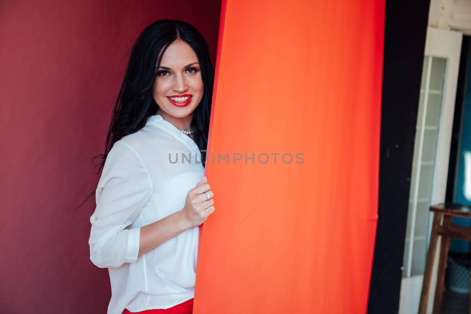 Portrait of a beautiful woman in a business suit in the office by the red wall