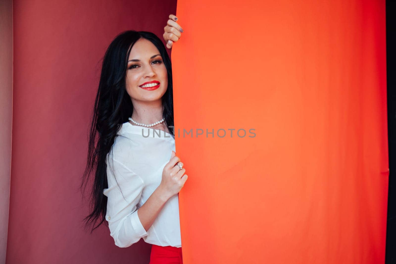 Portrait of a beautiful business woman in a business suit in the office by the red wall by Simakov