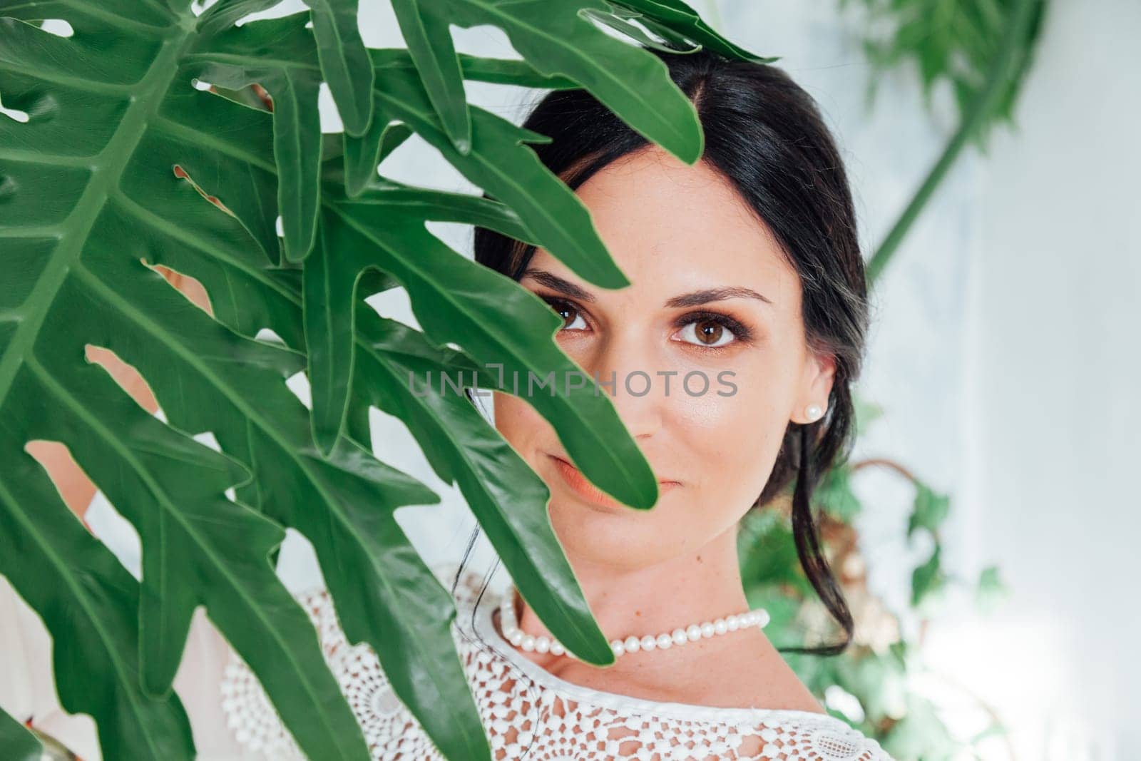 Portrait of a beautiful brunette woman with a green plant