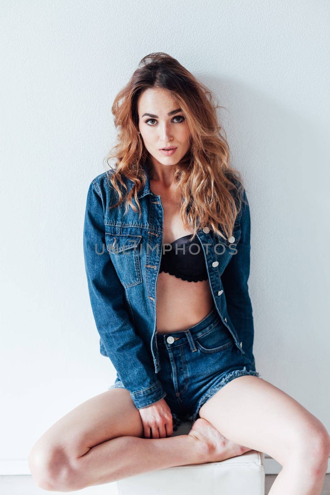 Portrait of a fashionable beautiful woman in denim shorts and lingerie by Simakov