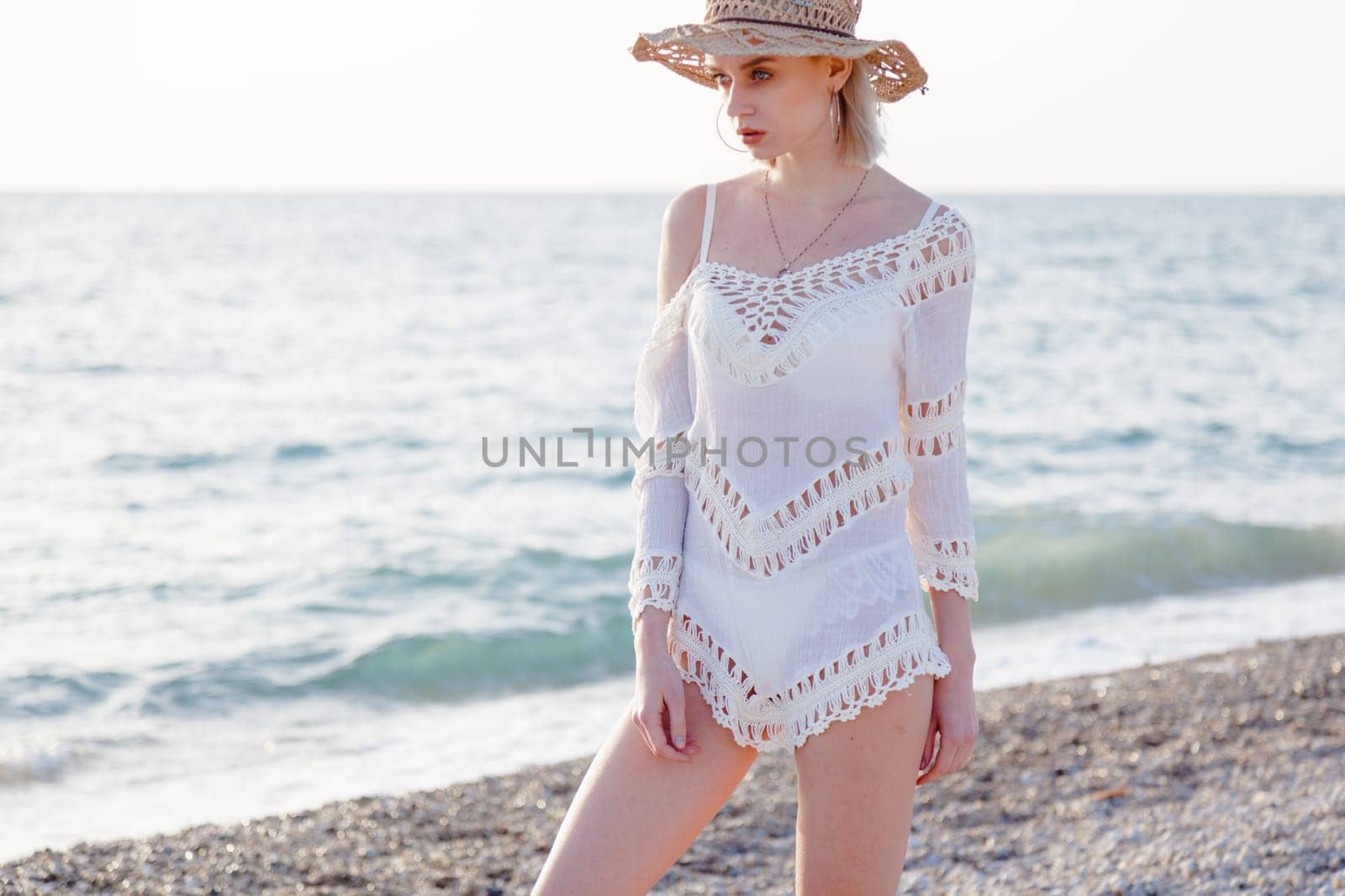Beautiful fashionable woman blonde in a white dress on the beach by the sea by Simakov