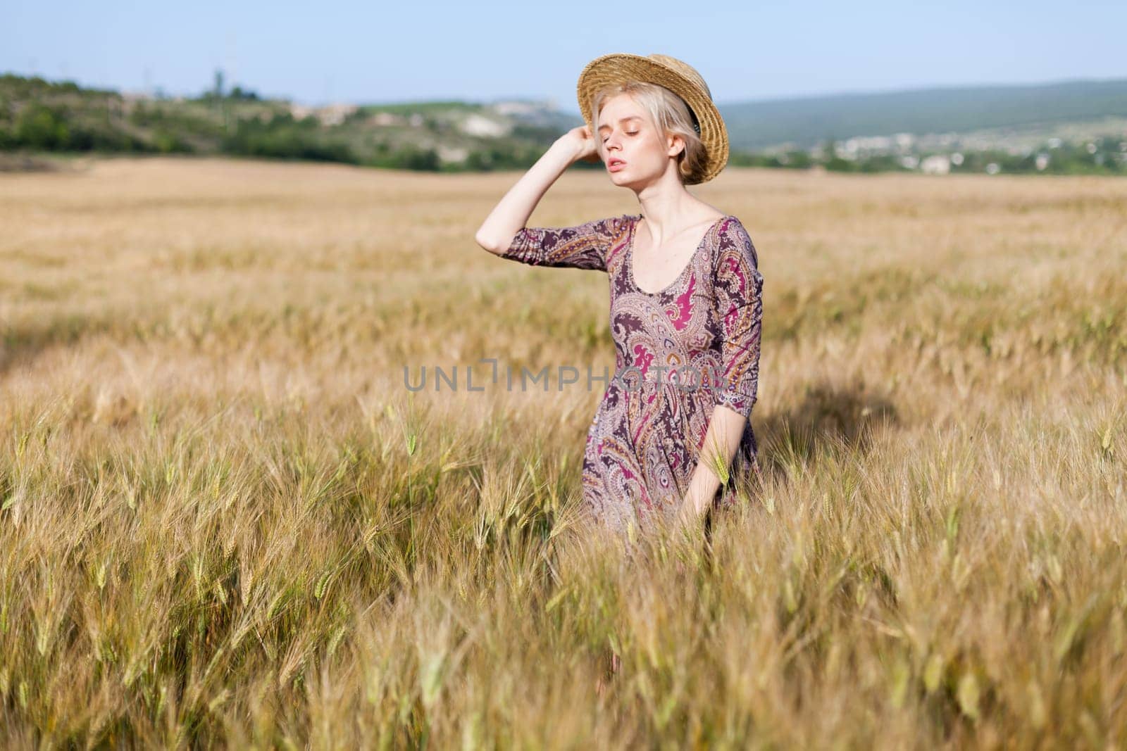 Beautiful fashionable woman blonde in a dress in a wheat field before harvest