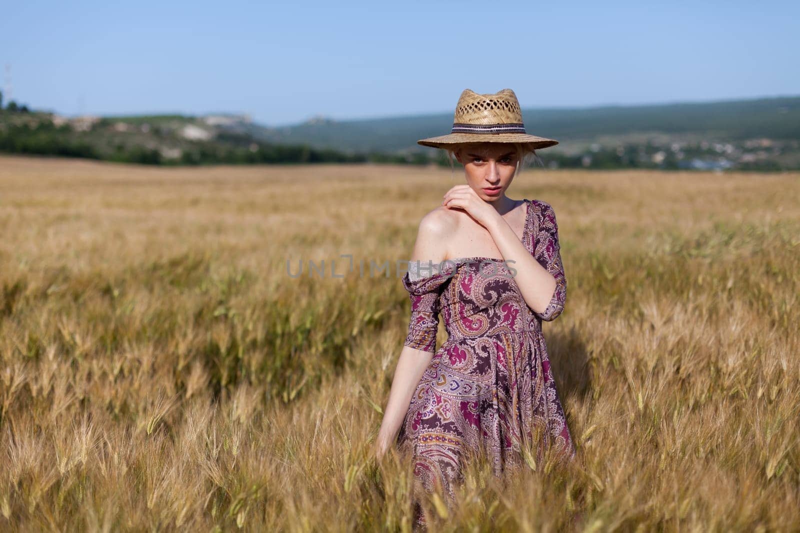 Beautiful fashionable woman blonde in a dress in a wheat field before harvest