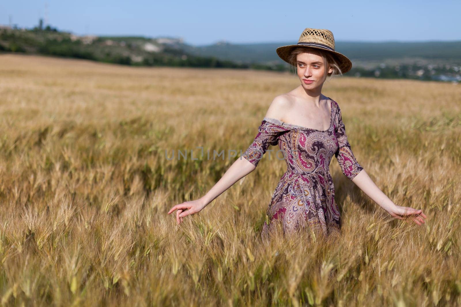 Beautiful fashionable woman blonde in a dress in a wheat field before harvest