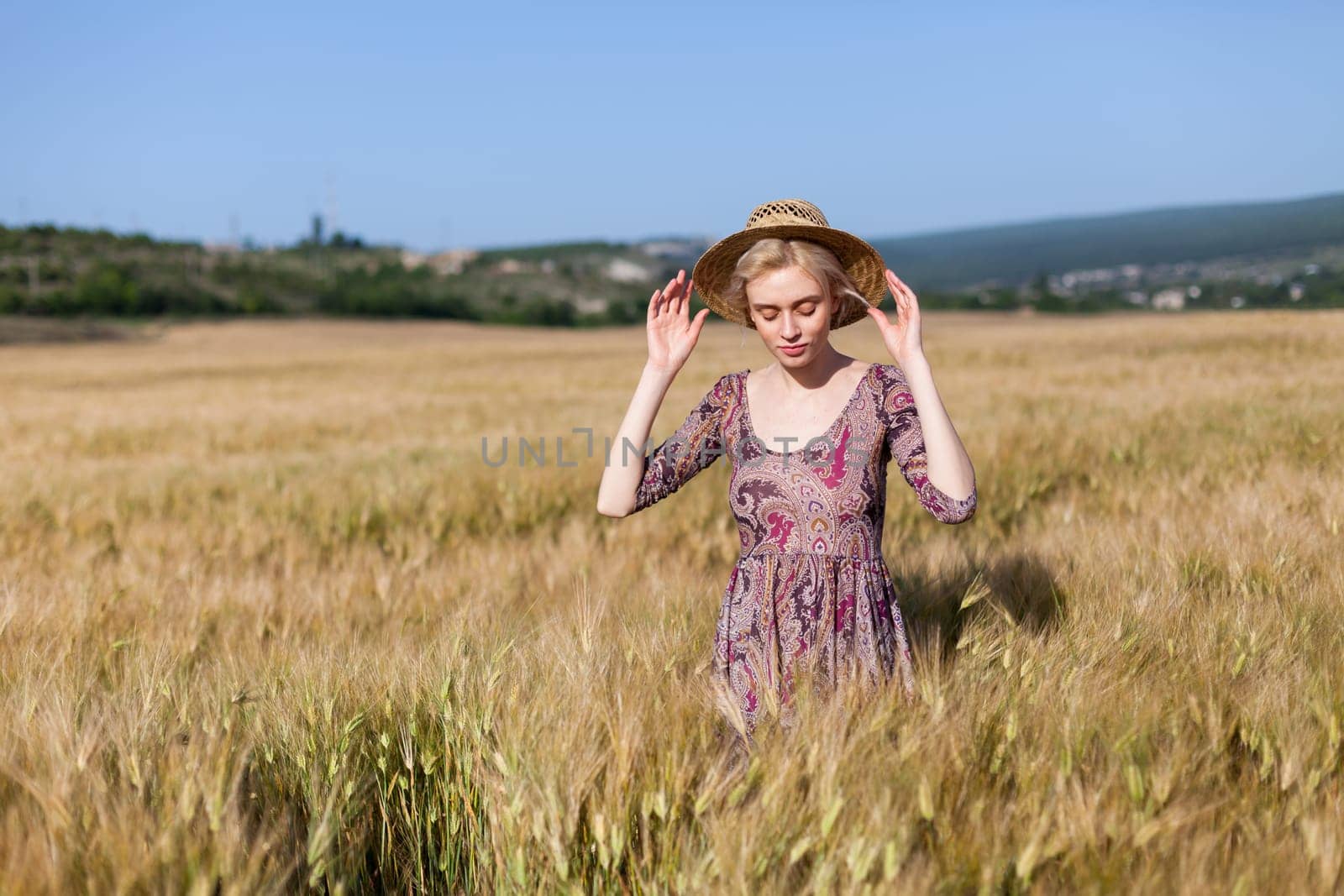 Beautiful fashionable woman blonde in a dress in a wheat field before harvest