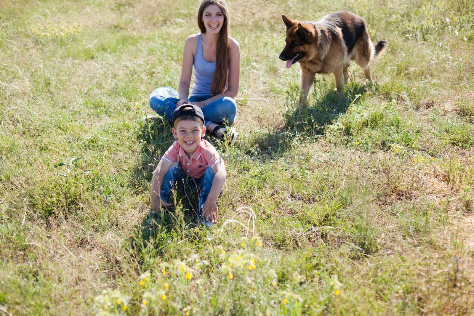 Beautiful woman with son plays with dog sheepdog on a walk