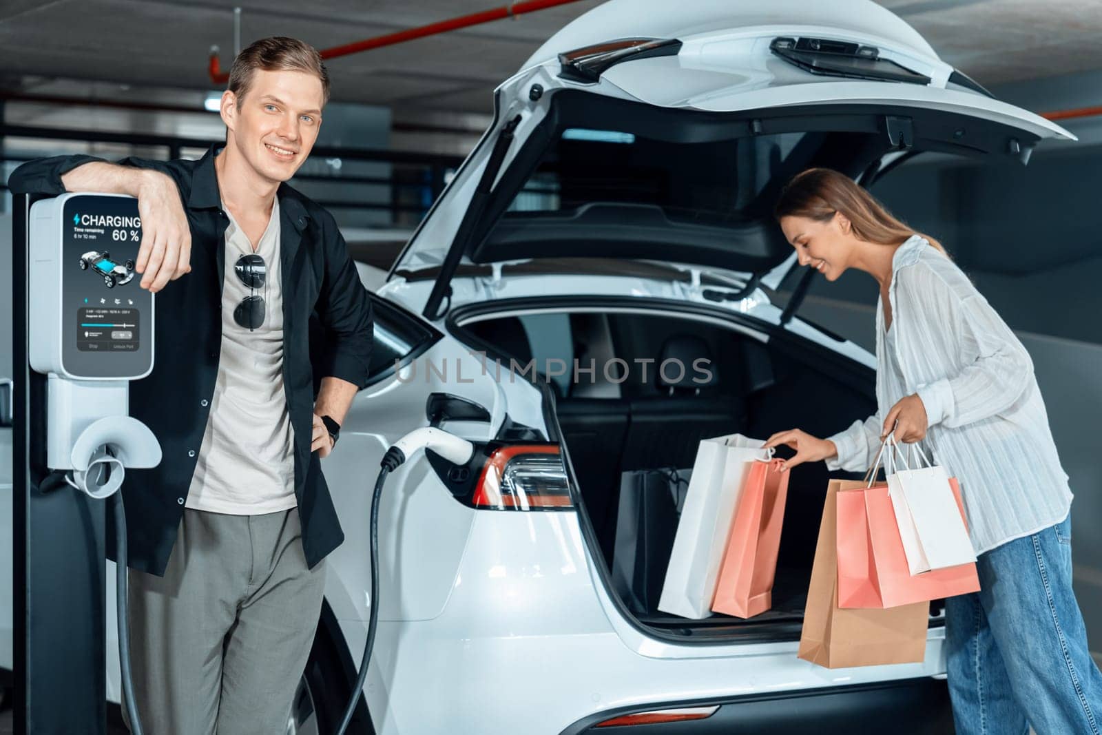 Young couple travel with EV electric car to shopping center parking lot innards by biancoblue
