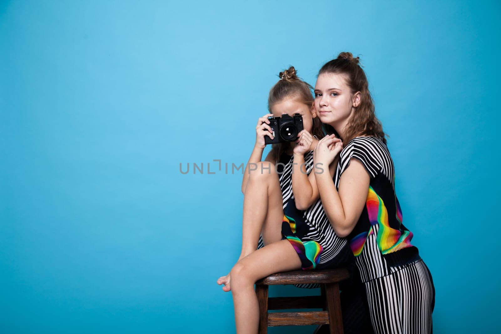 Portrait of two beautiful fashionable sisters girls with a camera by Simakov