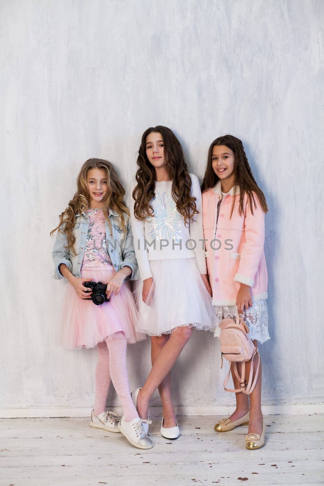 three beautiful fashionable girl girlfriends in pink and white dresses with a camera by Simakov