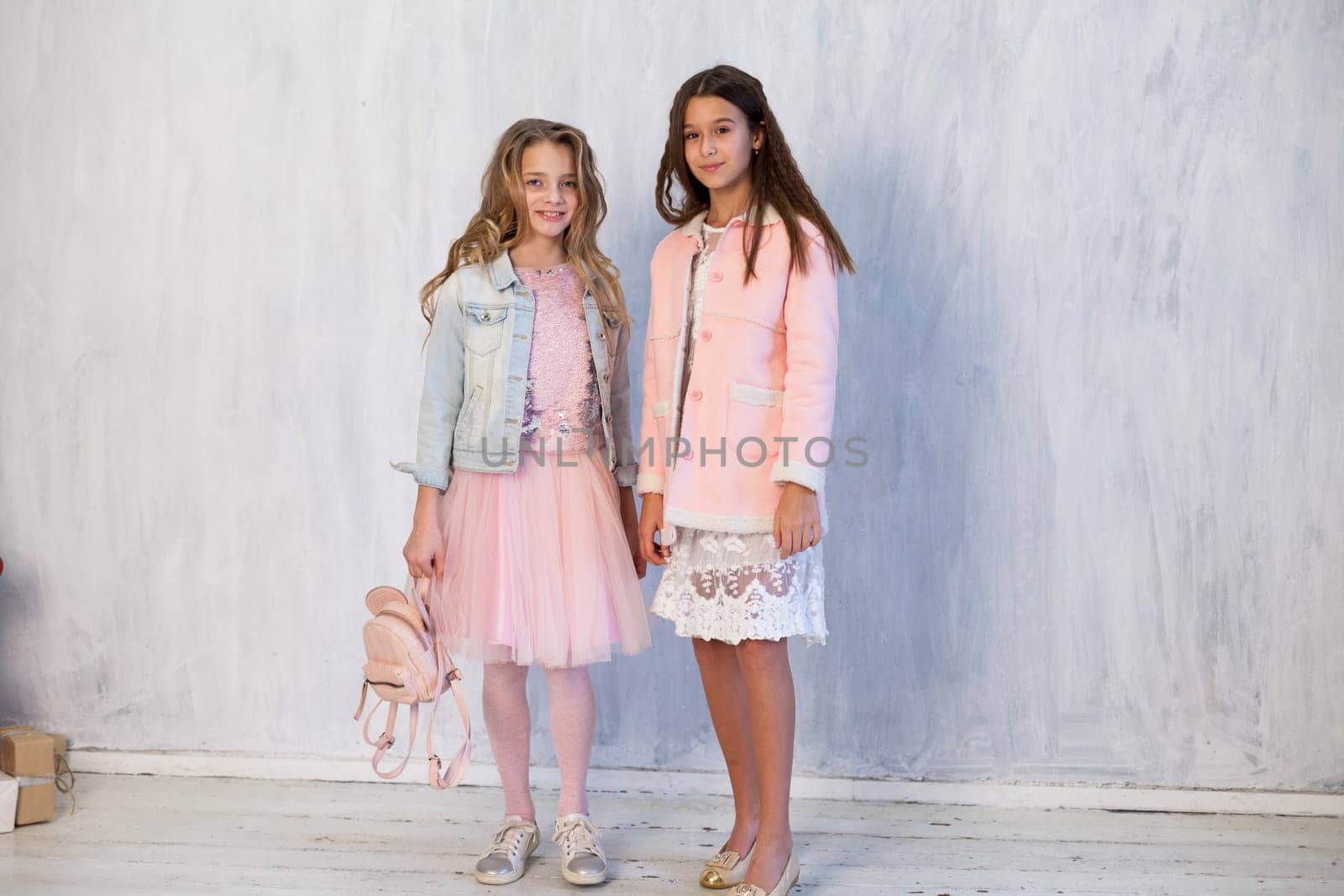 Two fashionable girl girlfriends in pink and white dresses