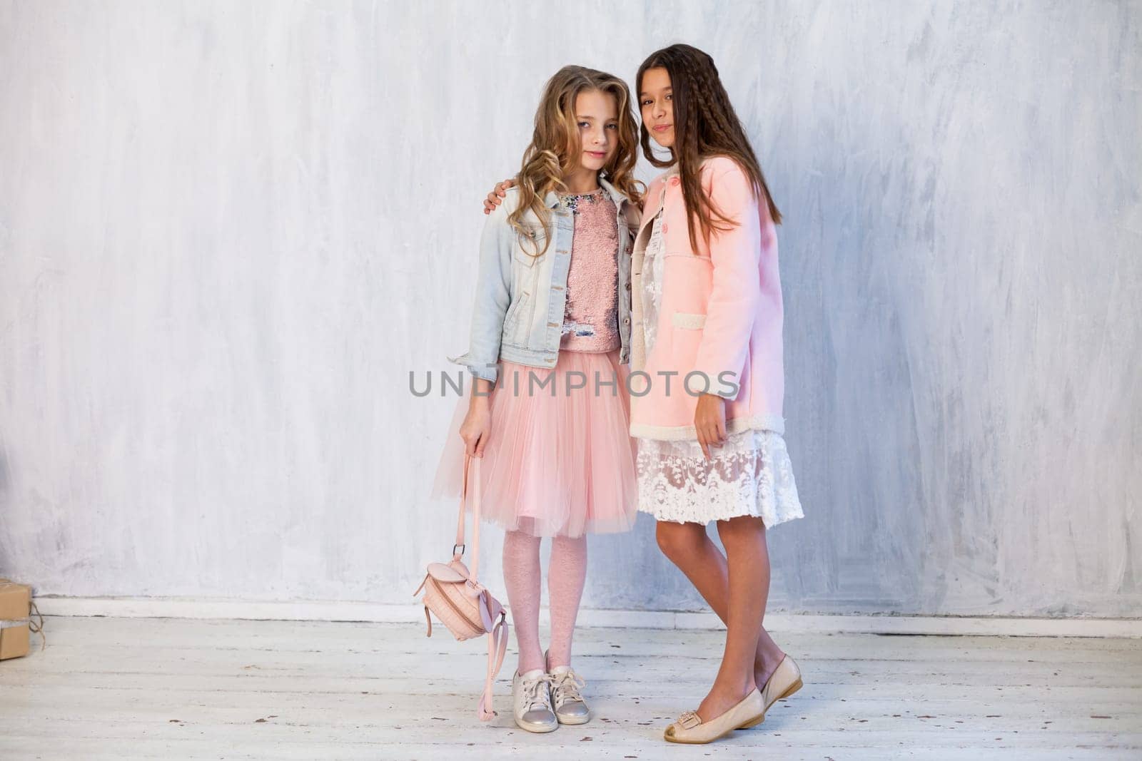Two fashionable girl girlfriends in pink and white dresses