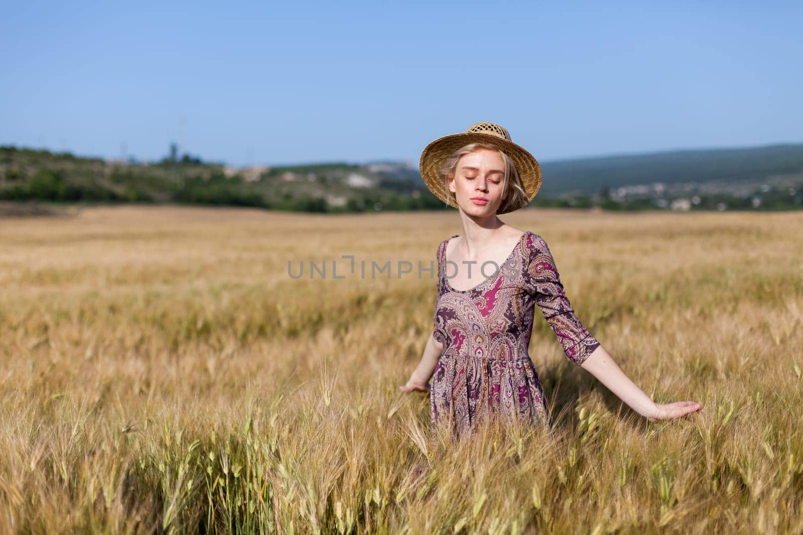 Portrait of a beautiful fashionable woman in a field before harvesting on the farm