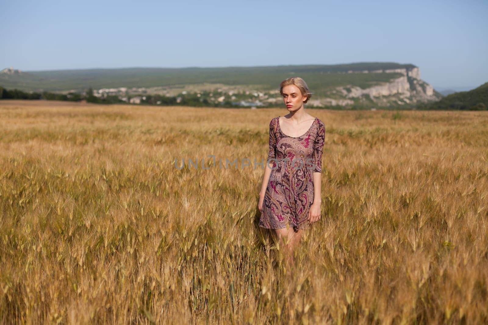 Portrait of a beautiful fashionable woman in a field before harvesting on the farm