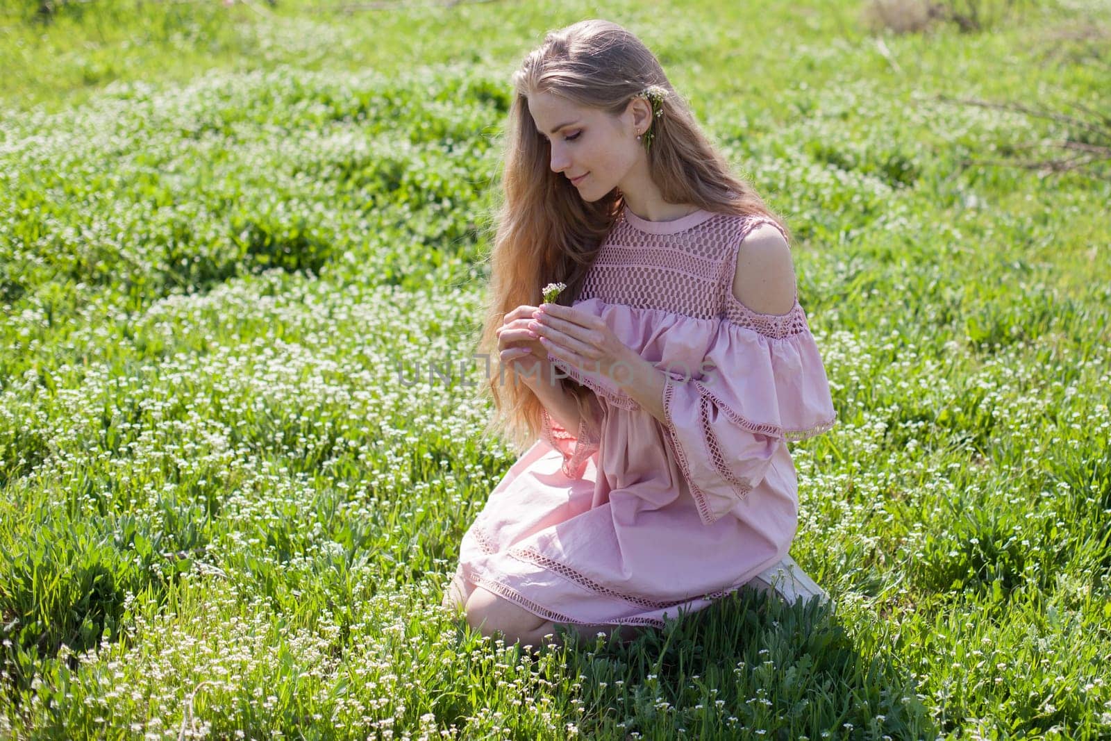 happy blonde woman in pink dress collects flowers in the flowering garden in spring