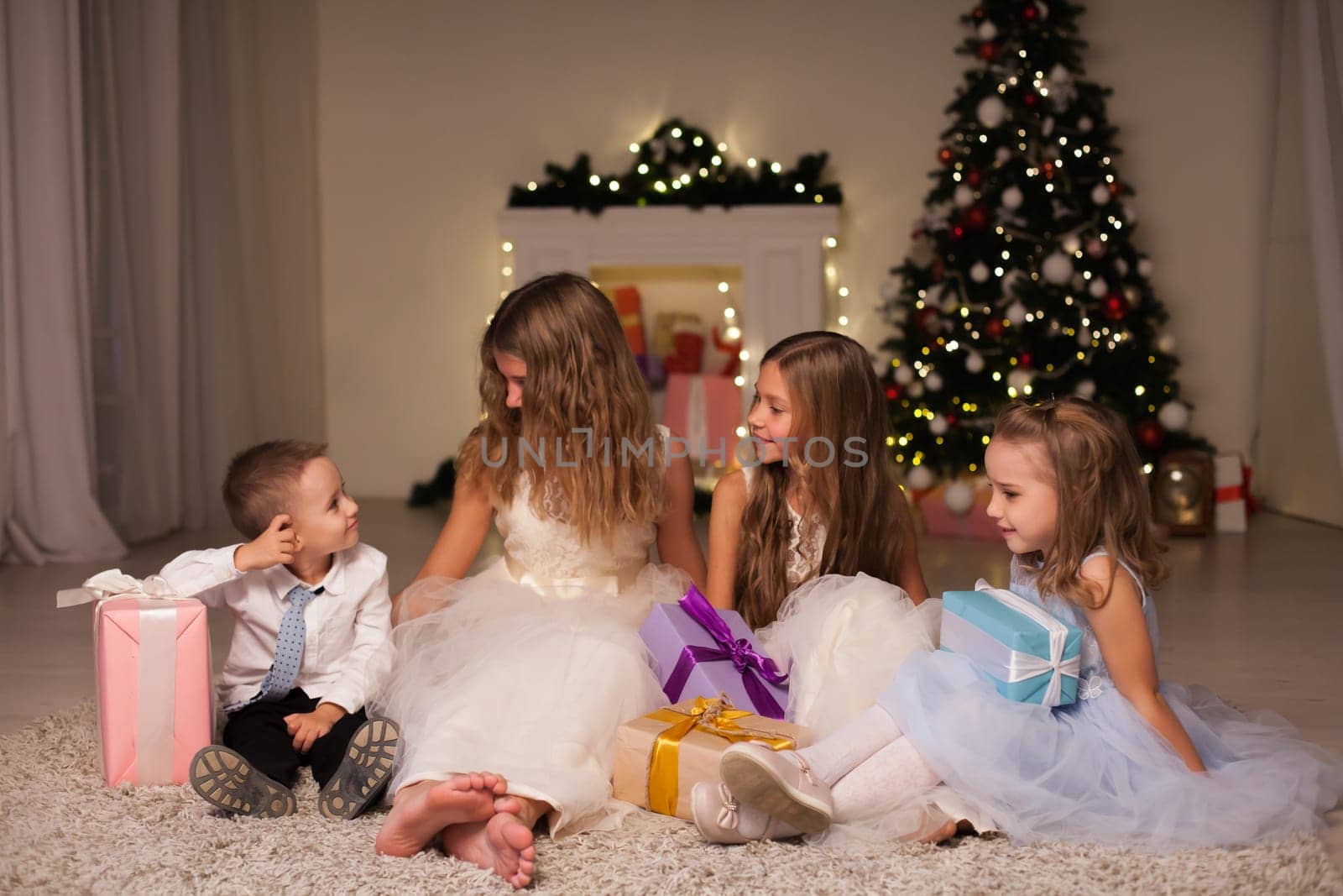 Kids family open gifts at New Year's Christmas Tree by Simakov
