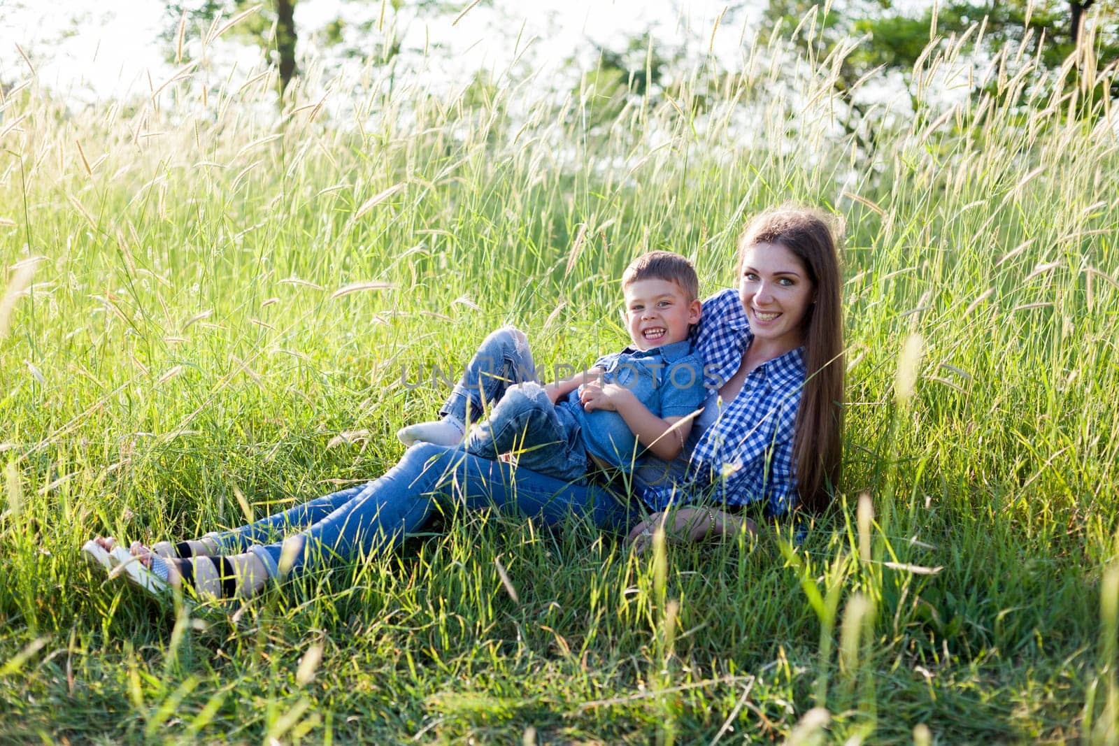 Portrait of a beautiful woman with her son on a walk in nature by Simakov