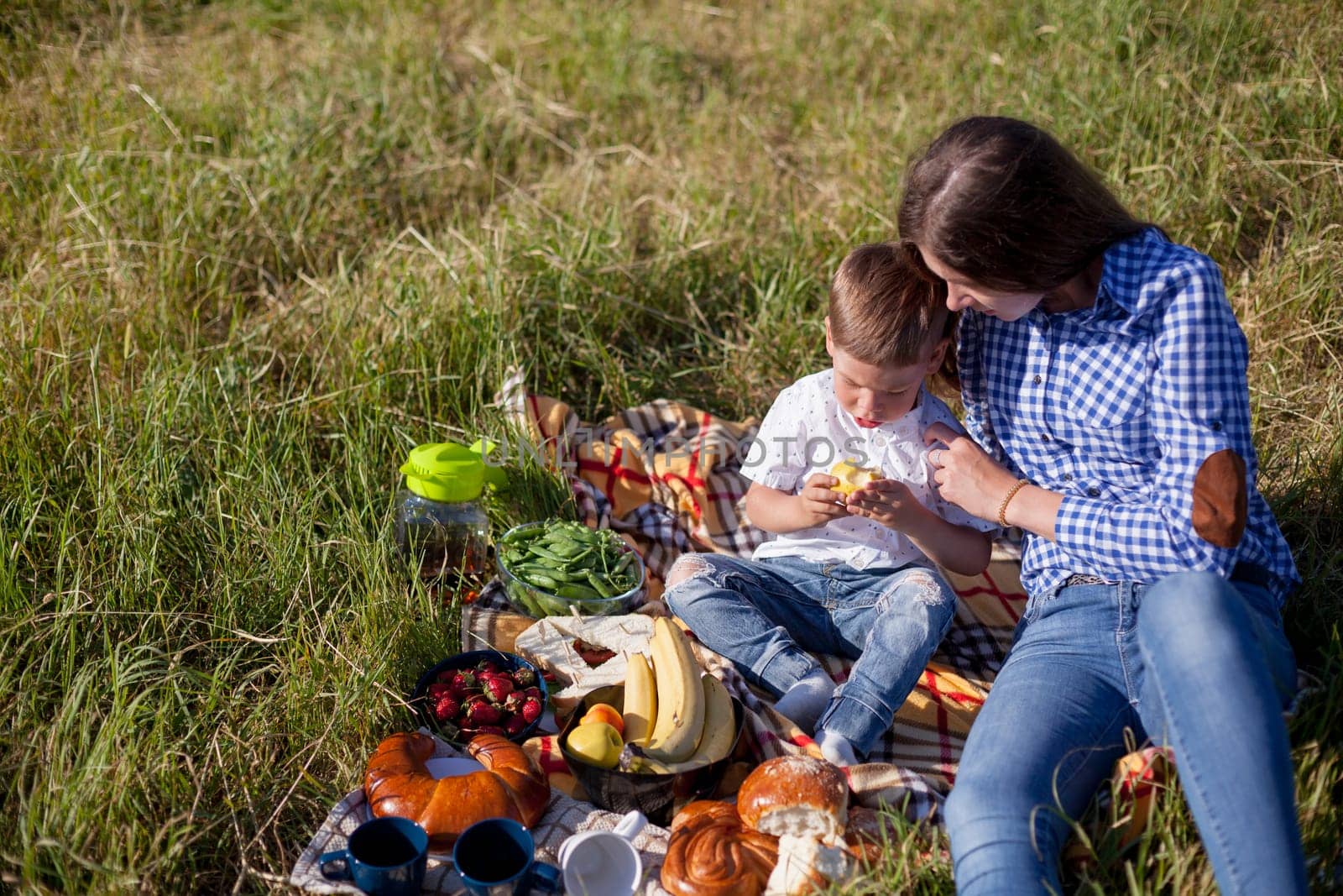 Beautiful woman with her beloved son on a picnic in the woods