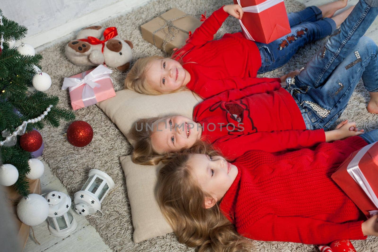 Three little girls open gifts at the Christmas tree new year winter by Simakov