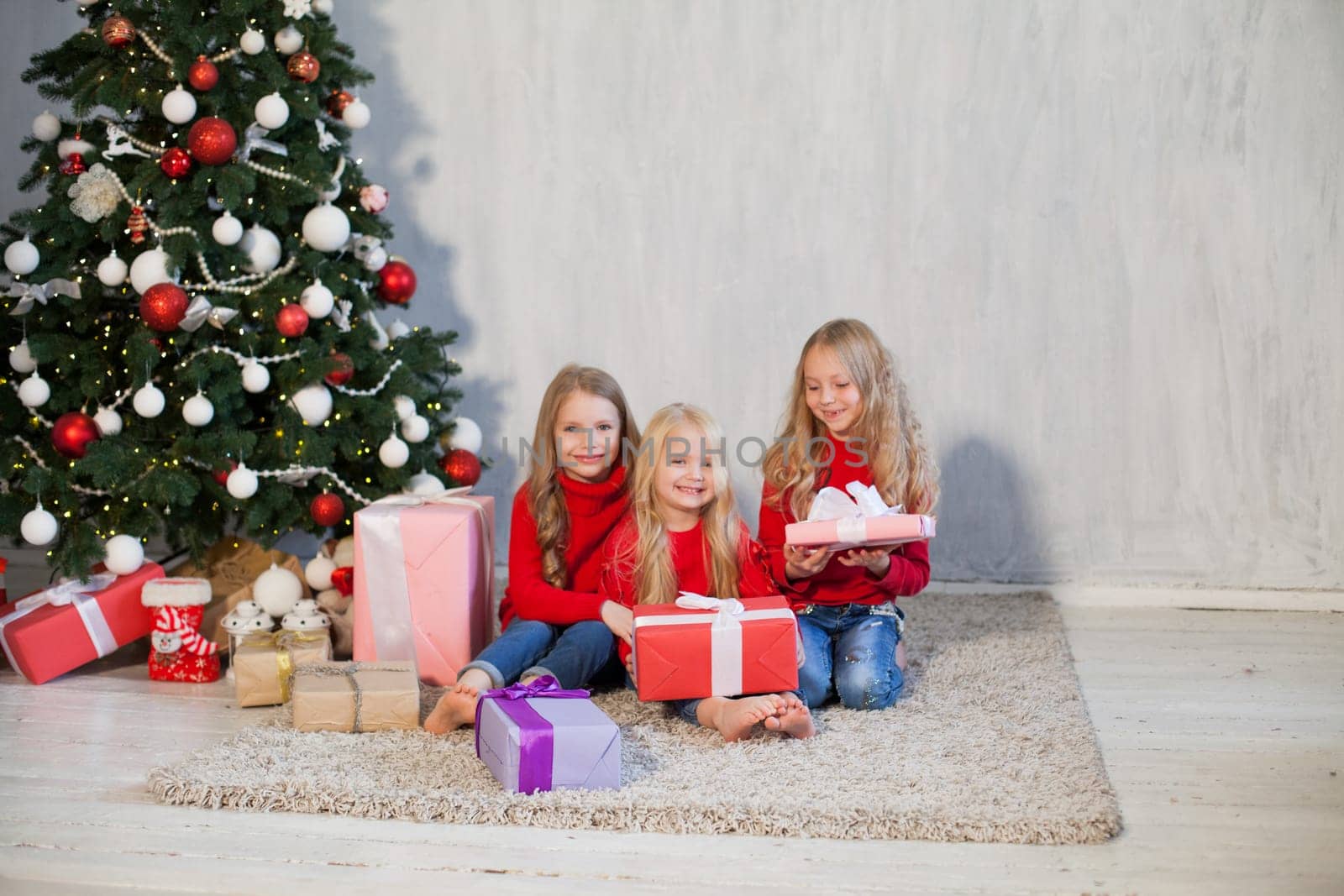 Three little girls open gifts at the Christmas tree new year winter by Simakov