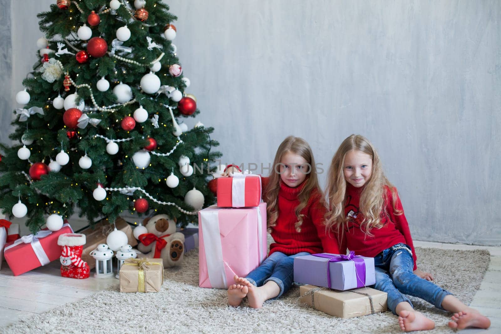 Two little girls opens gifts at the Christmas tree new year winter by Simakov