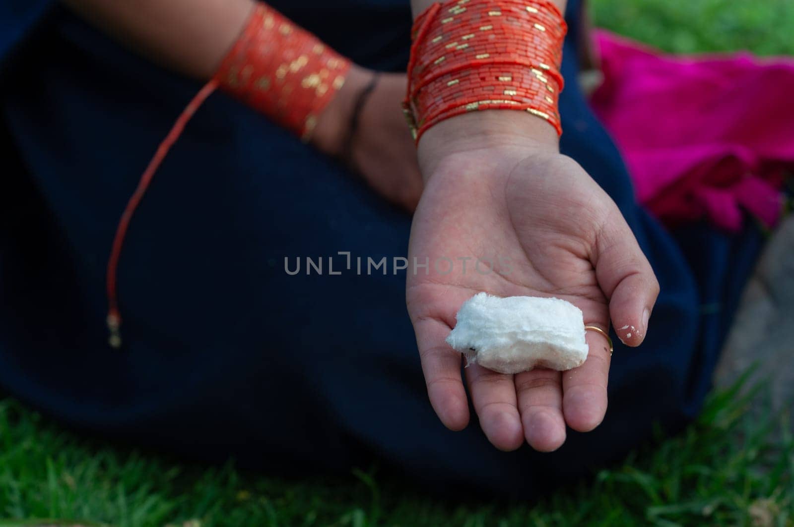 Horizontal shot of the hands of an indigenous woman from Ecuador with her orange cuffs on her wrists showing a large guaba seed before eating it. guaba day. High quality photo