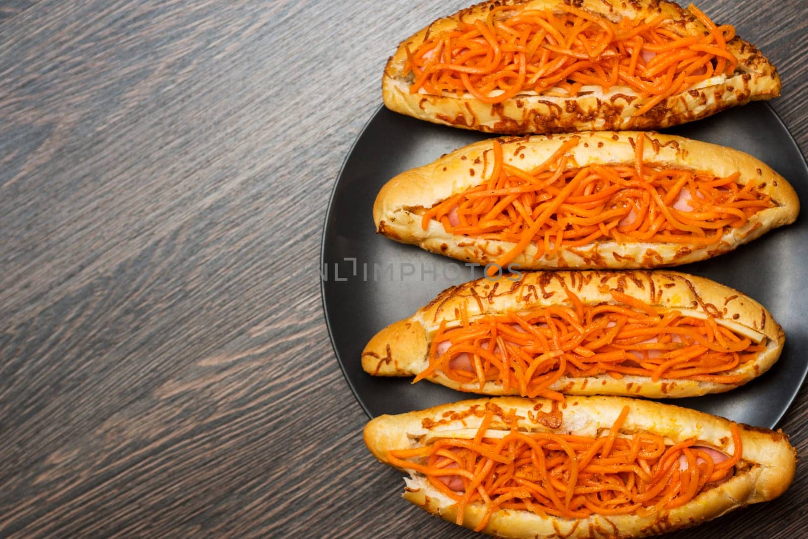 Tasty hot dogs on a black plate on a wooden background. Top view, copy space.