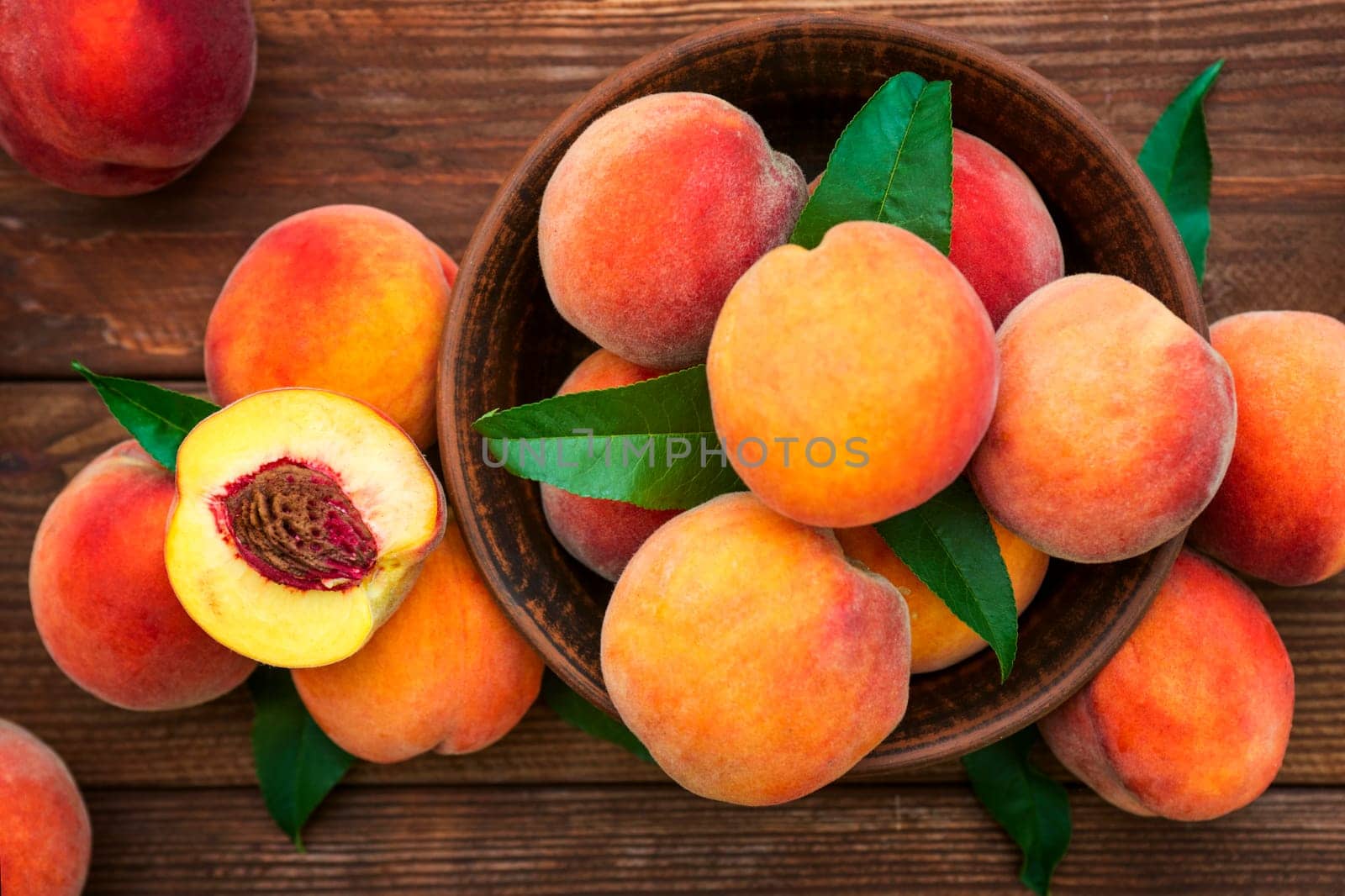 Ripe and tasty and juicy peaches lie on a plate on a wooden table. Large peaches on rustic wooden background, selective focus.