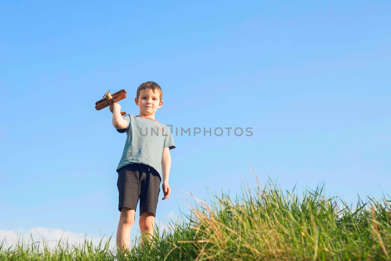 Little boy plays with a toy wooden plane. Child holds a toy wooden plane.